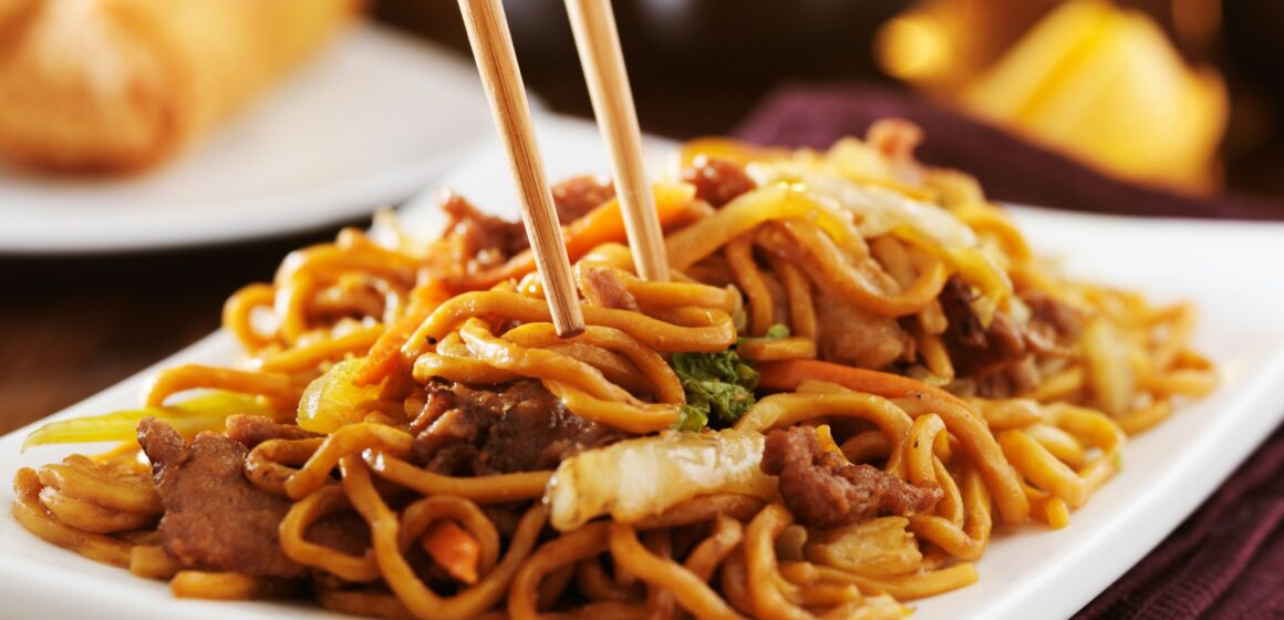 eating chinese beef lo mein with chopsticks